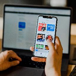 person using smartphone and laptop at the same time